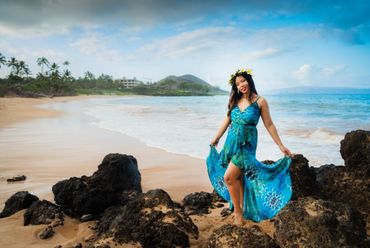 Young Maui pregnant woman standing at lava rock at Maluaka beach.