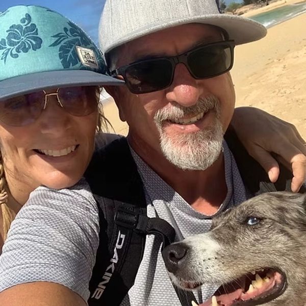 Smiling couple with a dog at the beach.
