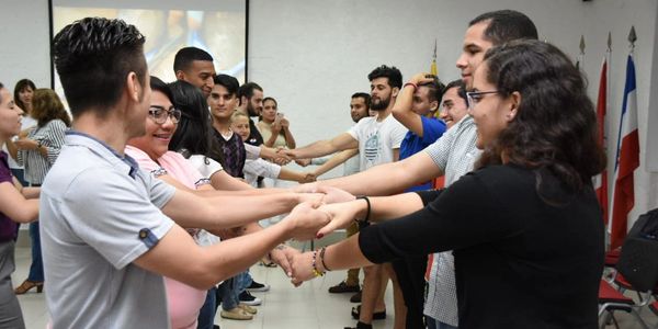 People in pairs holding hands and facing each other in an indoor setting.