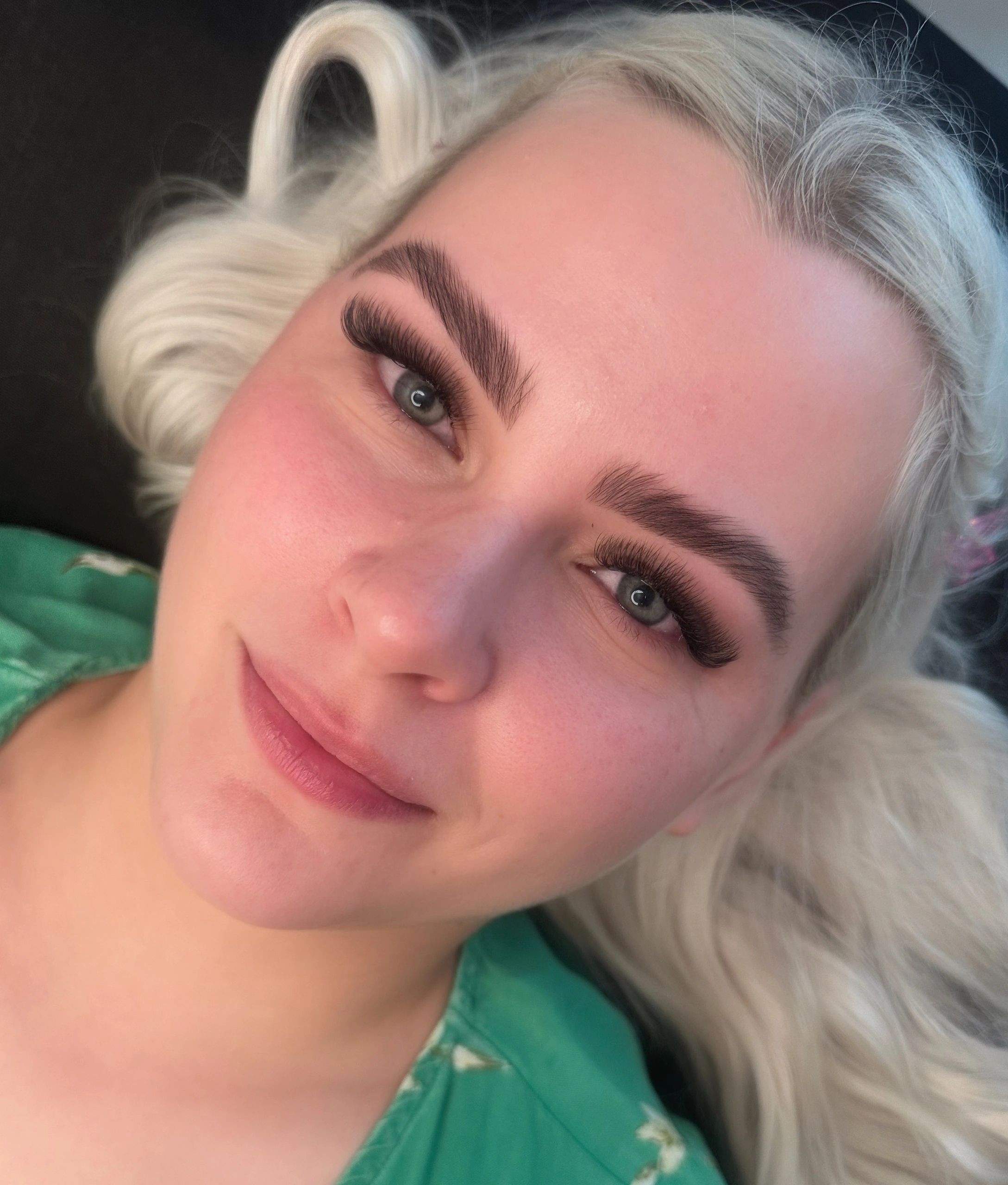 Close-up of a smiling woman with platinum blonde hair and volume lashes
