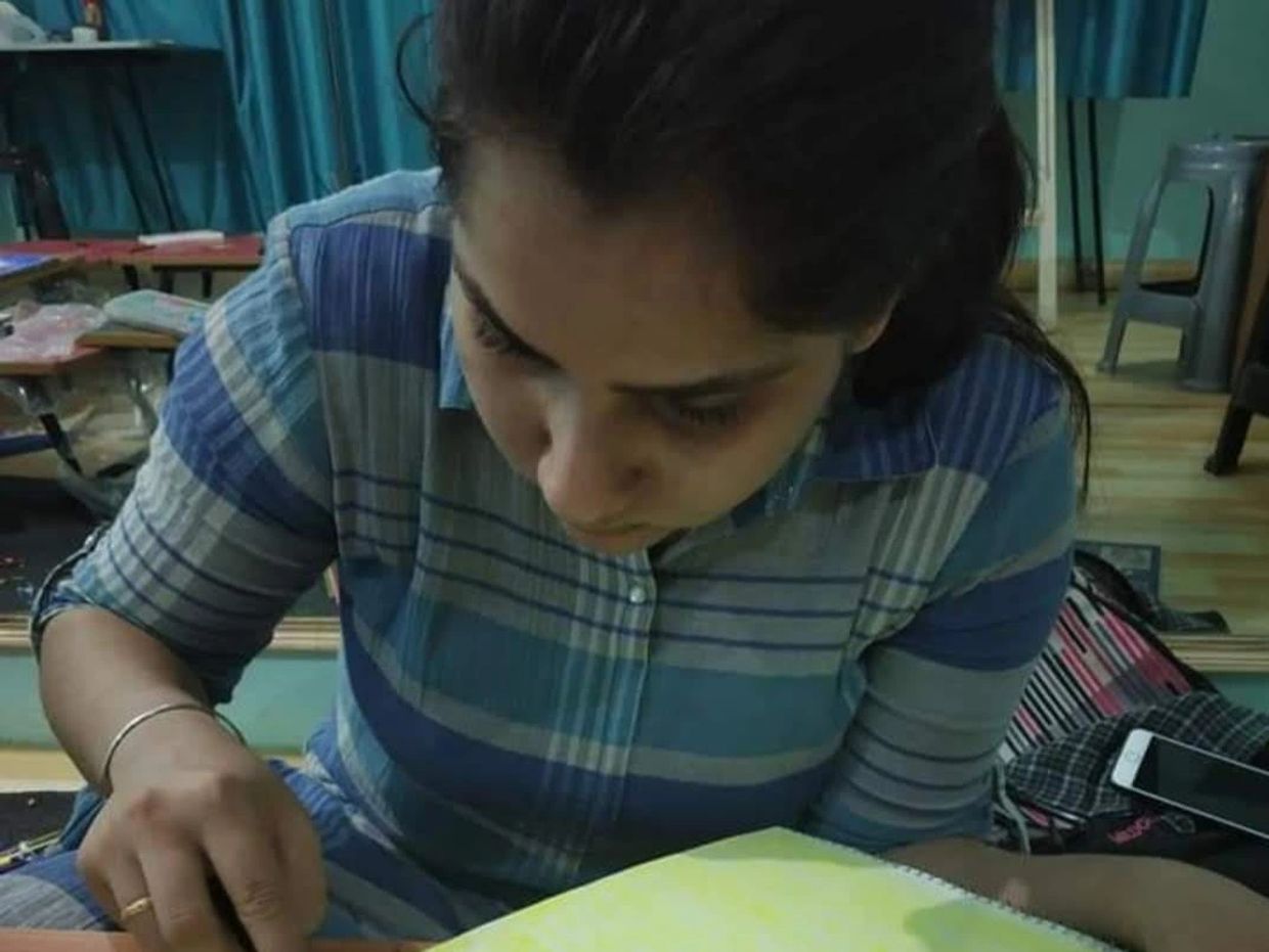 Young woman focused on writing in a notebook indoors.