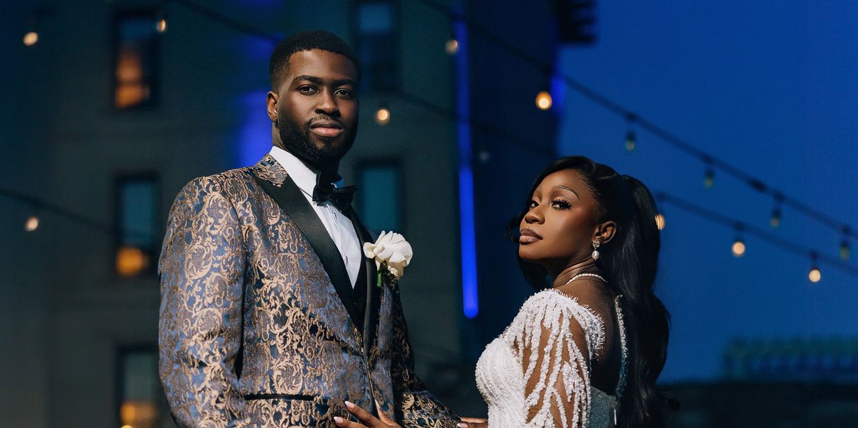 Elegant couple dressed in wedding attire under string lights at night.