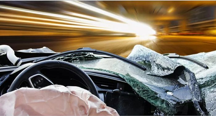 View from inside a crashed car with deployed airbags and shattered windshield.