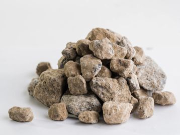 Pile of rough, irregularly shaped brownish-gray stones on a white surface.