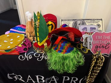 Colorful birthday props including hats, glasses, and signs on a black tablecloth.
