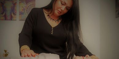 A woman performing a healing or massage therapy on a person lying down.