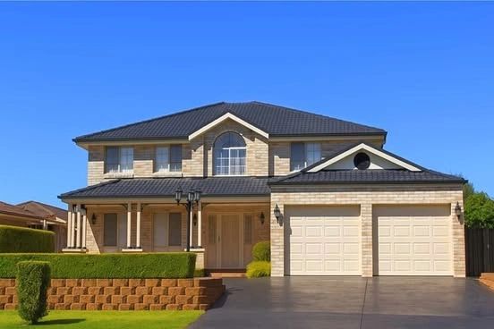 Exterior view of a large, two-story residential house with brick facade, dark roof, and two garage d