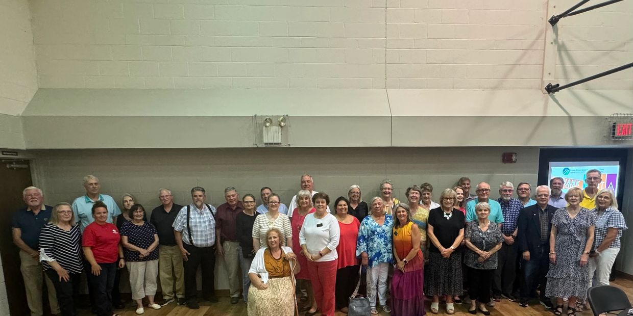 Large group of adults standing indoors for a photo.