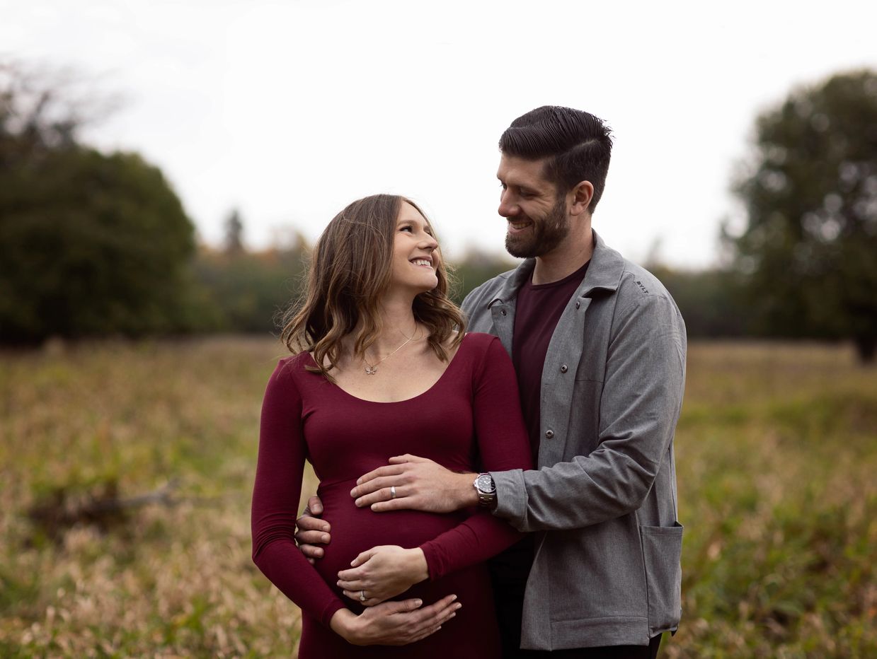 Happy couple smiling at each other while their hands are on her pregnant belly