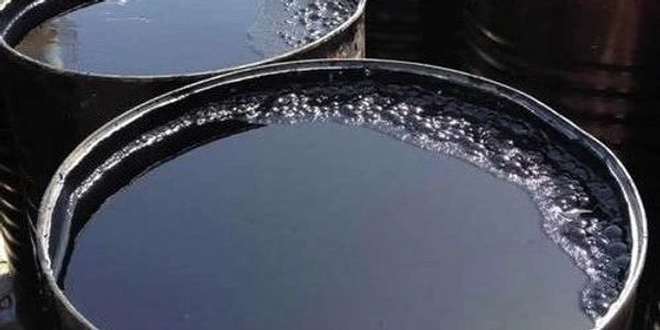 Close-up of barrels filled with black liquid, possibly crude oil.