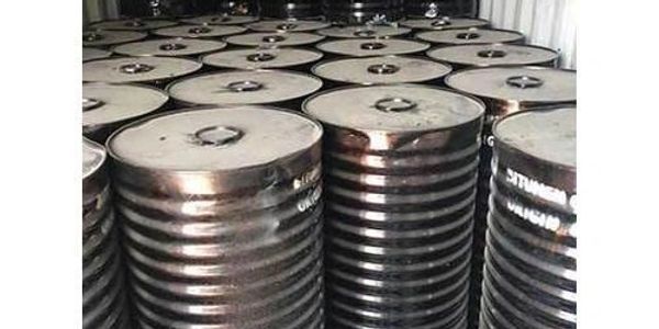 Stacked metal barrels with closed lids in a storage area.