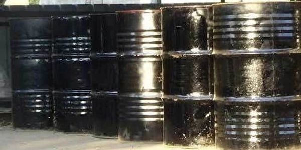 Stacked black metal barrels in an outdoor setting.