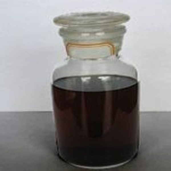 A glass jar filled with dark liquid on a gray surface.