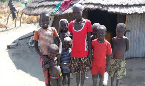 South Sudan refugee children in a refugee camp, standing in front of hut