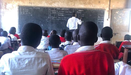 Children at the Gulu School in Uganda listening to a teacher teach at the blackboard