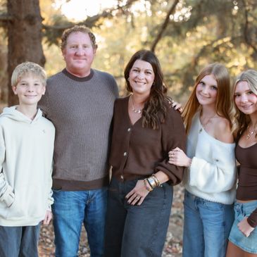 A happy family of five posing outdoors in casual autumn attire.