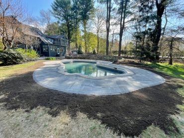 House with a pool surrounded by trees and garden.