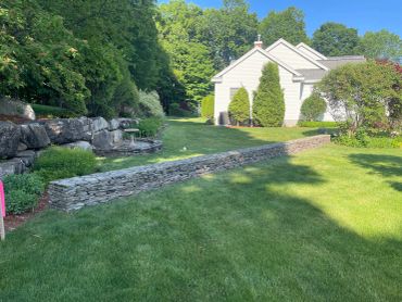 Well-maintained lawn with stone walls and greenery.