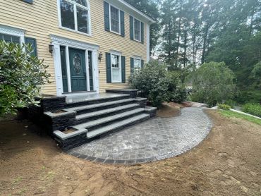Elegant entrance with stone steps and cobblestone pathway.