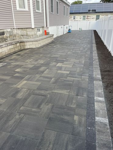 Newly installed patio with patterned pavers and white fence.