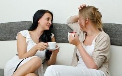 Two women talking about effective science-based skincare while drinking coffee