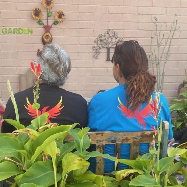 Two people sitting on a bench in a garden with matching phoenix shirts.