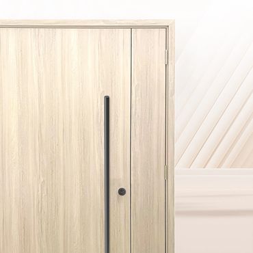 Modern wooden door with sleek black handle in a light-colored room.