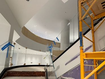 Interior under construction with stairs and glass railing.