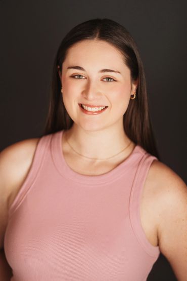 Ellie Abbott smiling in a light pink sleeveless shirt.