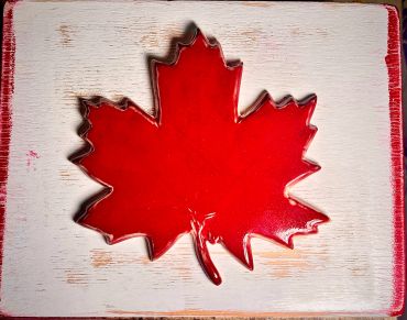 Bright red maple leaf decoration on rustic whiteboard.