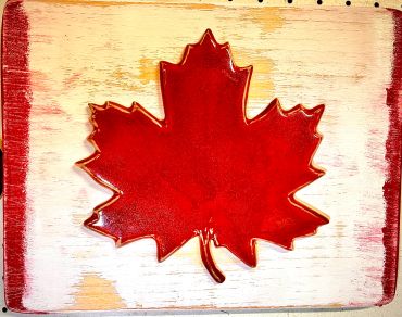 Glossy red maple leaf on a rustic wood background.