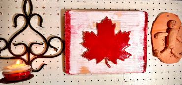 Decorative Canadian maple leaf sign on a pegboard wall.