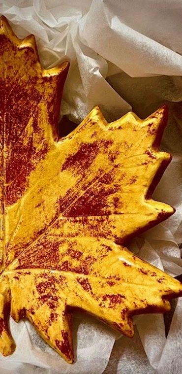 A close-up of a decorative autumn maple leaf with vibrant yellow and red tones.