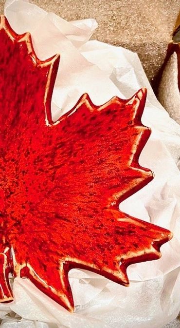 A red ceramic plate shaped like a maple leaf.