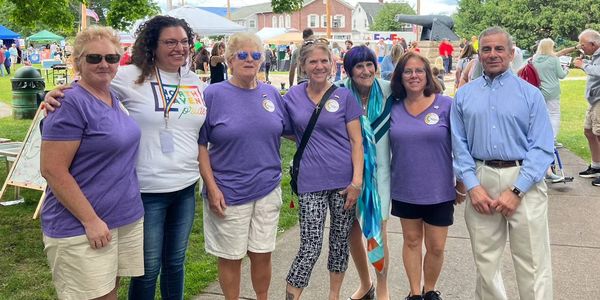 Group of seven people posing outdoors at a community event.