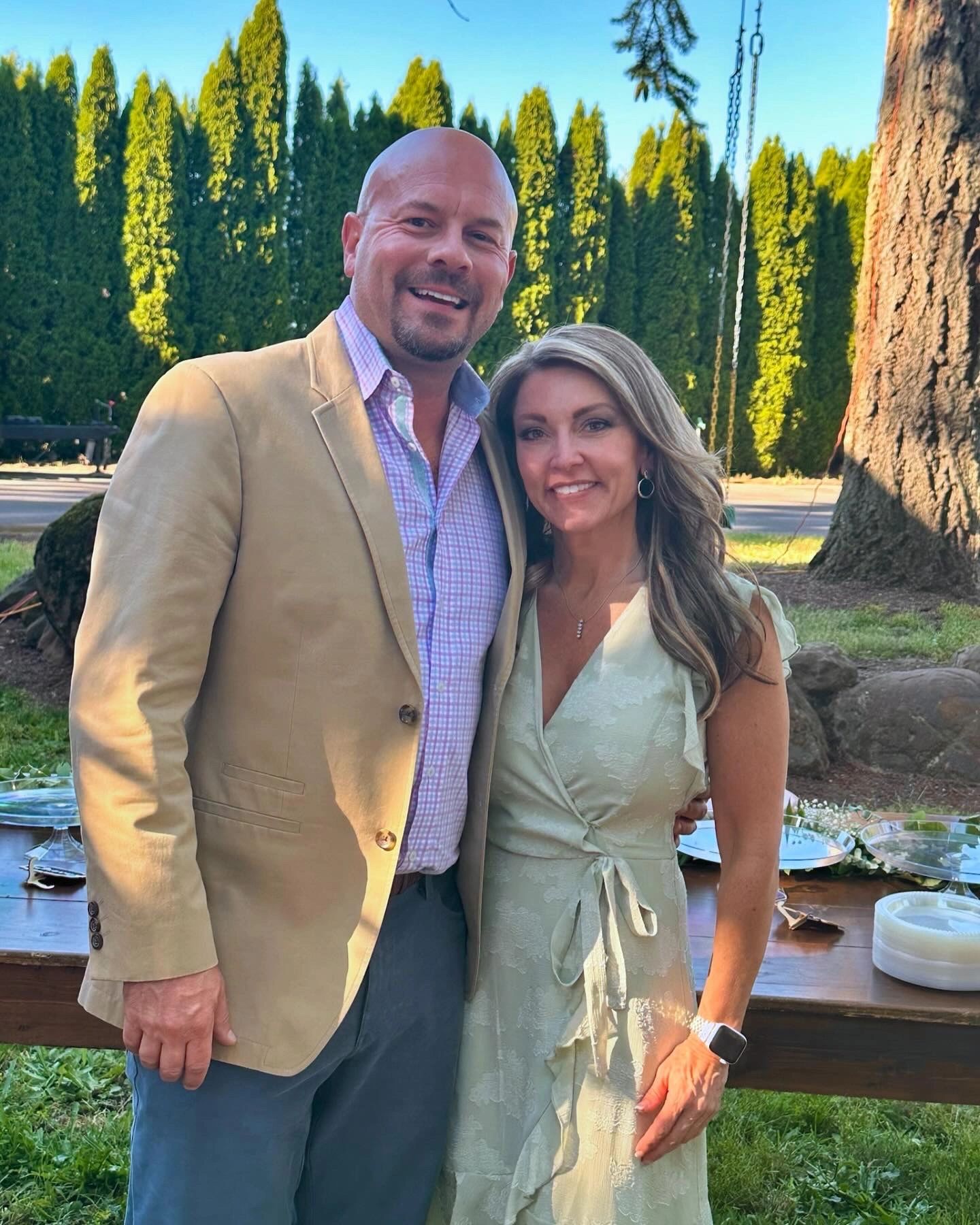 Smiling couple posing outdoors in formal attire.