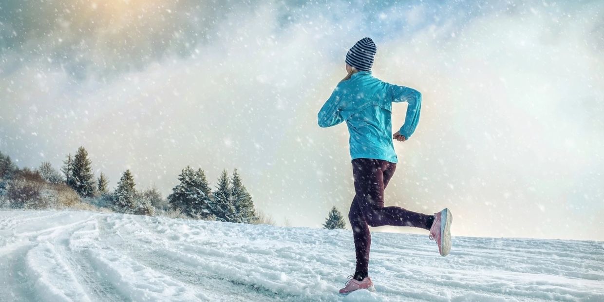 Women running on snow in waterproof jacket, leggings and running shoes.