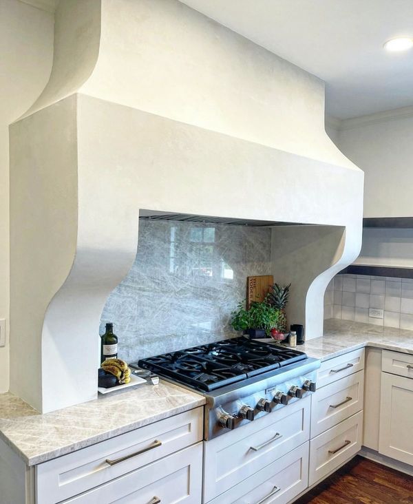 Modern kitchen with a stylish stove and unique hood design.