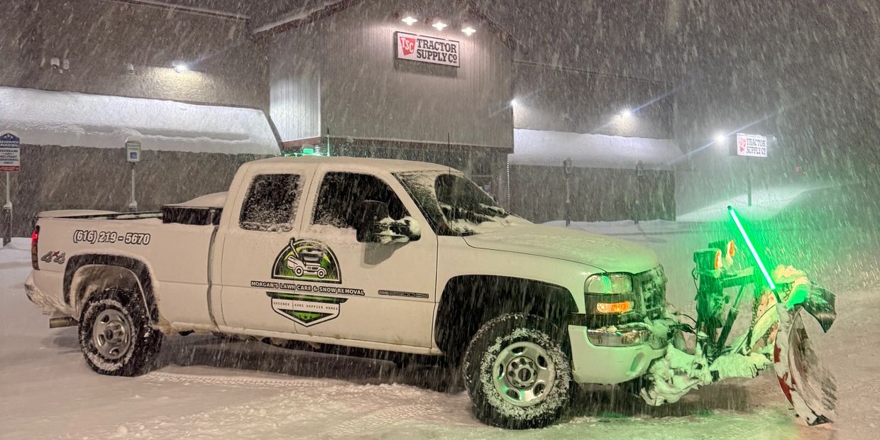Snow-covered truck with a plow in heavy snowfall at night.