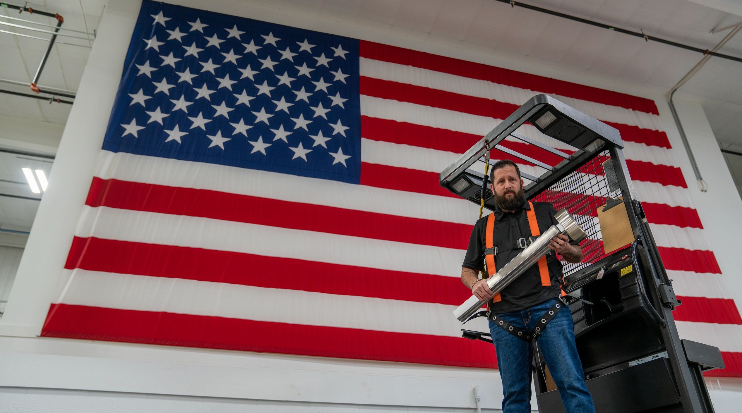 PDQ Manufacturing employee holding 6300 exit device in front of USA flag to symbolize made in USA