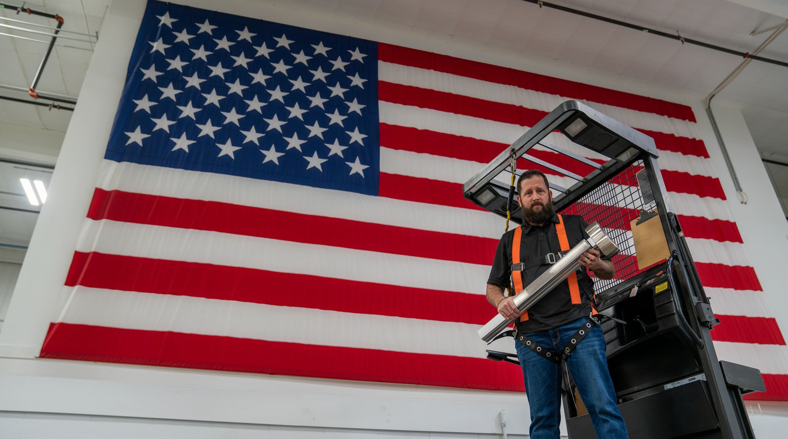 PDQ employee holding 6300 exit device in front of United States flag to symbolize made in the USA