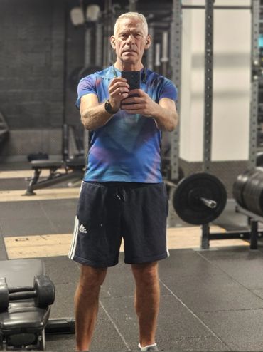 Man taking a gym mirror selfie in workout attire.