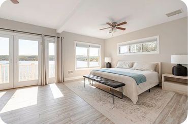 Bright bedroom with lake view, light wood flooring, and minimalist decor.