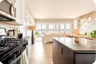 Bright modern kitchen and living area with large windows and staircase.