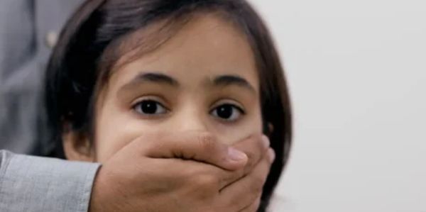 A young girl with a hand covering her mouth, looking worried.