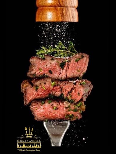 Seasoned steak pieces on a fork being sprinkled with salt.