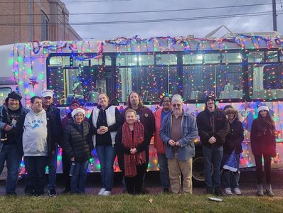 Group of people posing in front of a bus decorated with colorful lights.