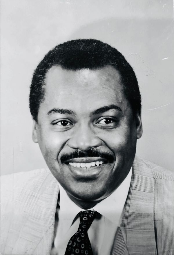 Black and white portrait of a smiling man in a suit and tie.