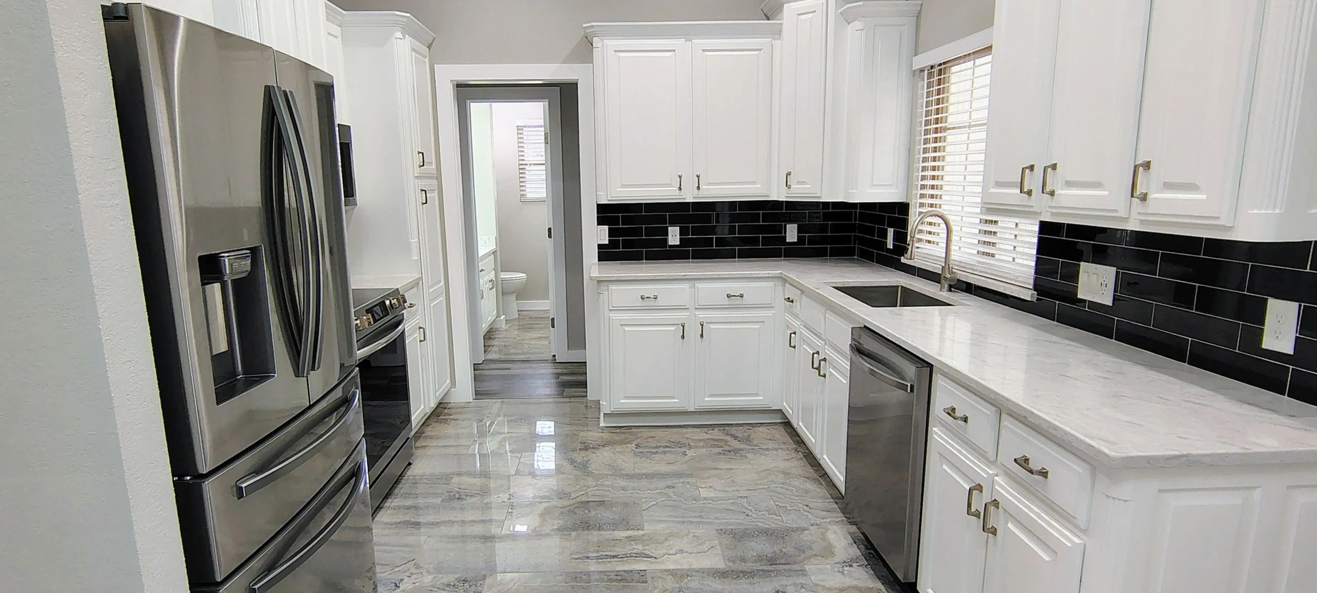 Modern kitchen with white cabinets and stainless steel appliances.