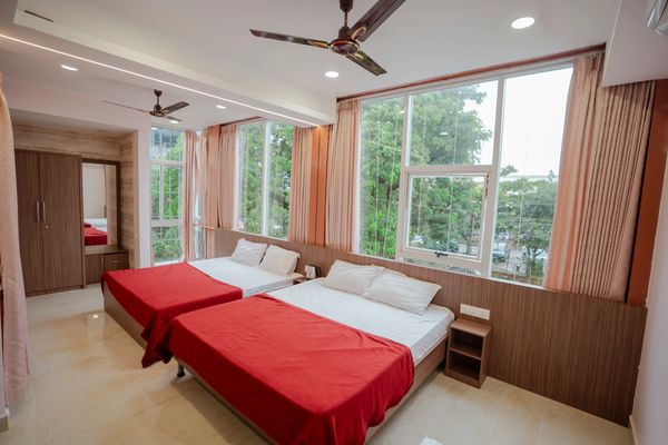 Bright bedroom with two beds and large windows.